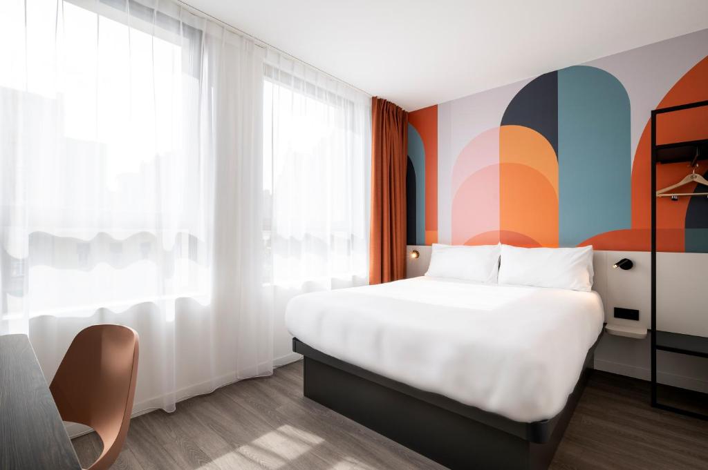 安特卫普B&B HOTEL Antwerpen Centrum的卧室配有白色的床和色彩缤纷的墙壁