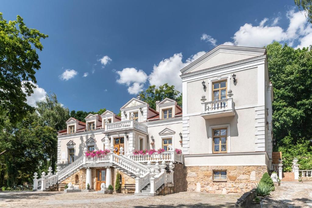 奥斯特罗维茨Pałac Tarnowskich Hotel & Restauracja & SPA的白色的房子,前面有楼梯