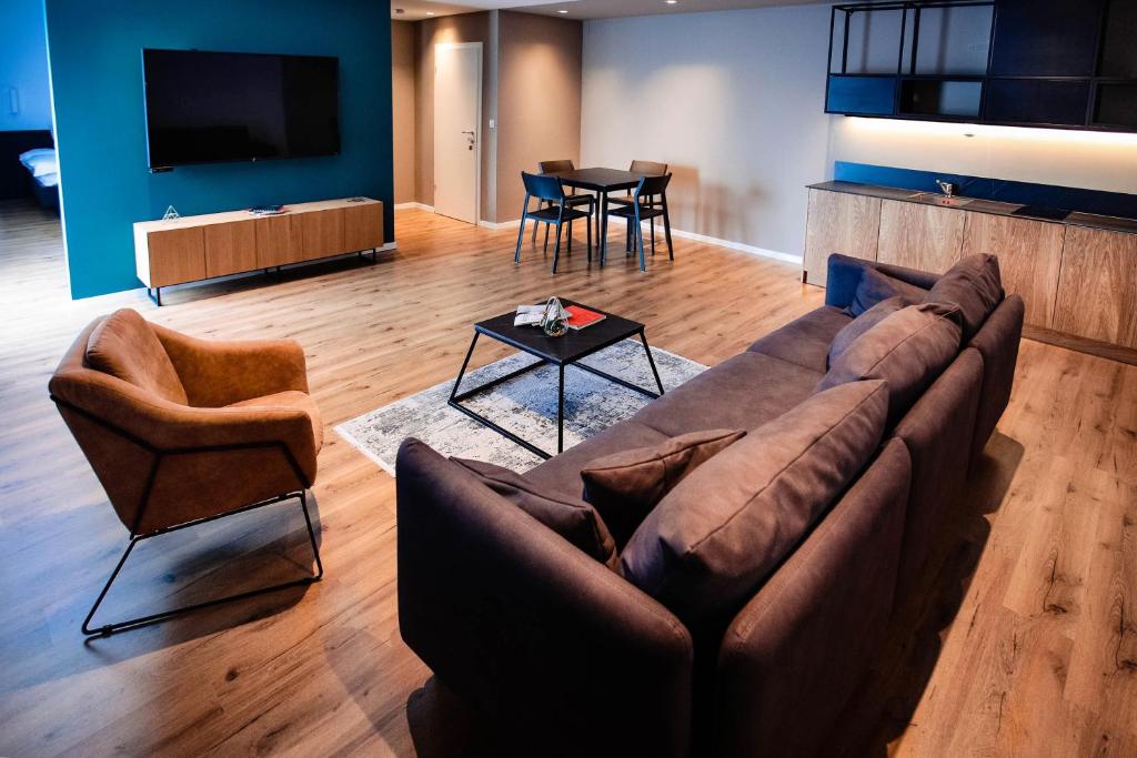 普里什蒂纳Swiss Apartments Prishtina的客厅配有沙发、两把椅子和一张桌子