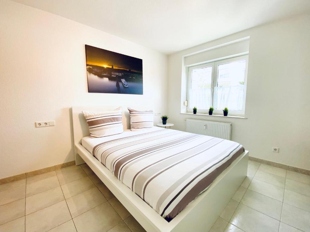 腓特烈港Auszeit Apartment BODENSEE mit 4 Schlafzimmern, 600 m Luftlinie bis zum Bodenseeufer, in unmittelbarer Nähe des Bodenseeradwegs, schöne Sonnenterrasse, schnelles Internet, für bis zu 5 Personen的白色卧室配有带条纹床单的大床