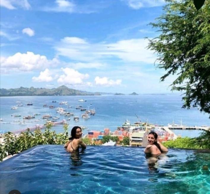 纳闽巴霍Bayview Gardens Hotel的两个女性在海景游泳池里