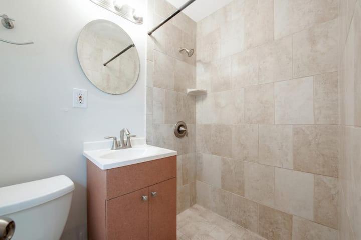 劳德代尔堡Studio Apartment By Pmi Edgewood的浴室配有水槽和带时钟的淋浴