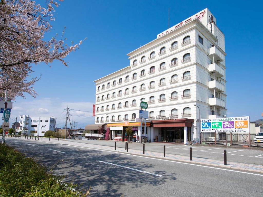 笛吹市Tabist Hotel Sun Plaza Fuefuki Isawa的街道边的白色建筑