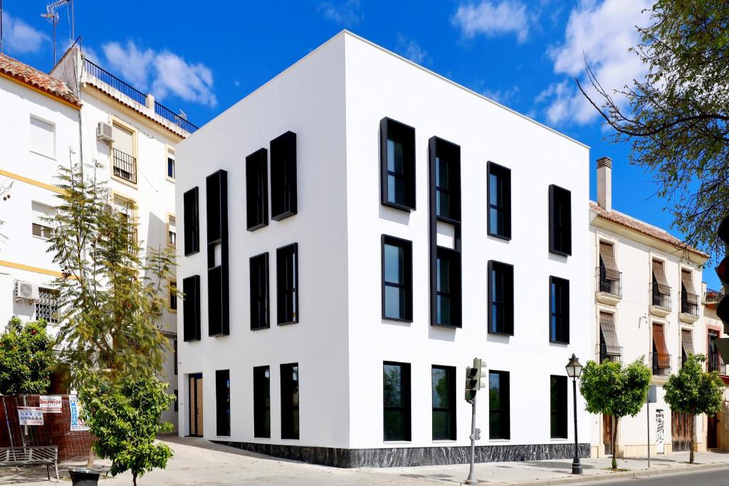 科尔多瓦Apartamentos Ribera 19的白色的建筑,在街上有黑窗