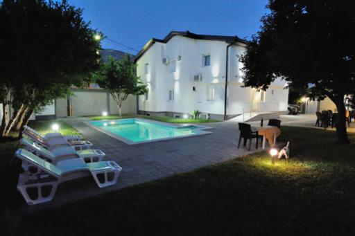 莫斯塔尔Villa Paradiso By Italy的一座带躺椅的游泳池位于大楼旁