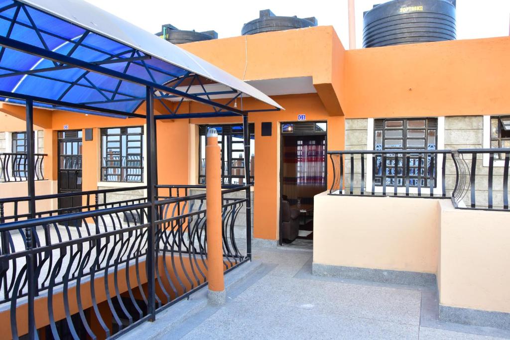 阿西里弗Amber Apartments G1 Kitengela的一座橙色的建筑,拥有蓝色的屋顶和一个阳台