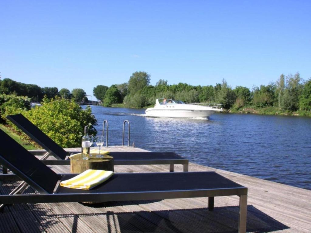 NigtevechtRiverside holiday home near Amsterdam的码头,设有两把椅子和一条船上