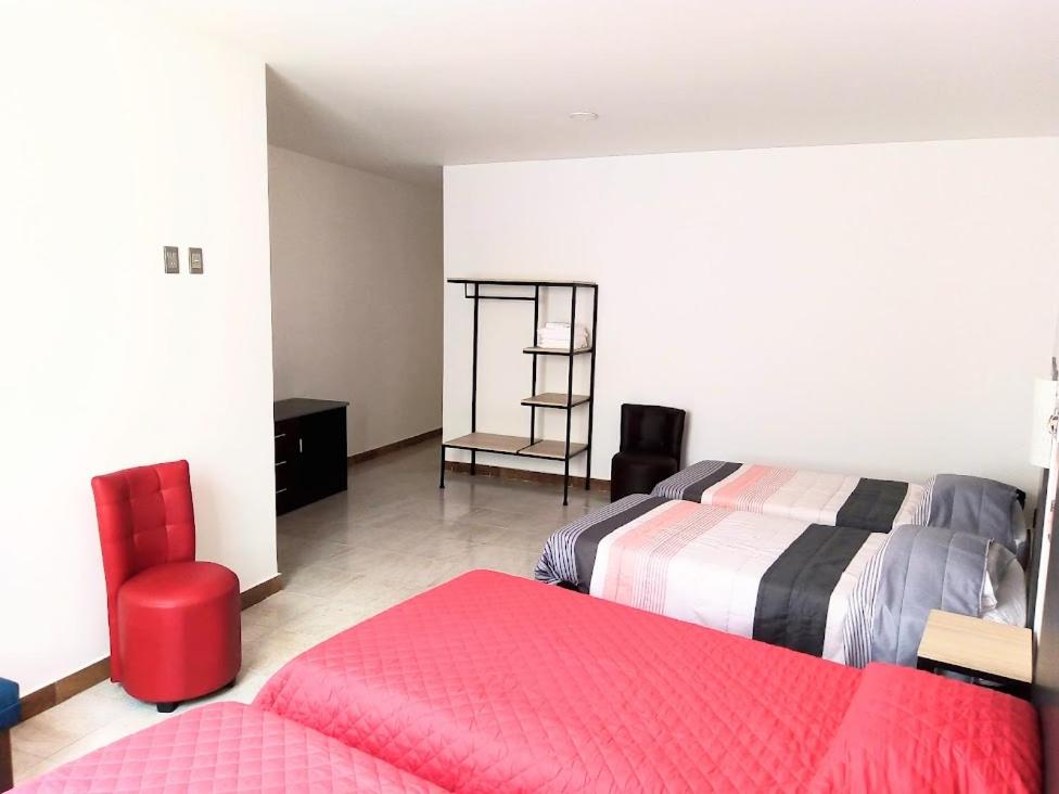 莱昂Casa Republik的一间卧室配有两张床和红色椅子