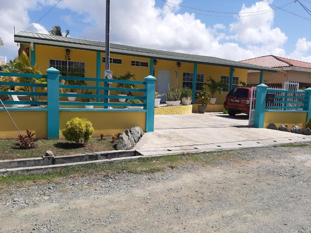LowlandsCC Best Villas Tobago的前面有蓝色栏杆的黄色房子