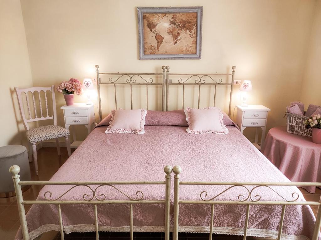 TuiliB&b il Giardino da Pina的一间卧室配有一张带粉红色床单的床和两把椅子