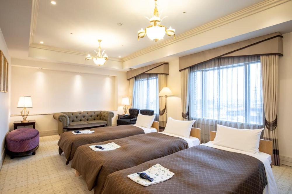 东京Hotel Cadenza Tokyo的酒店客房,设有两张床和一张沙发