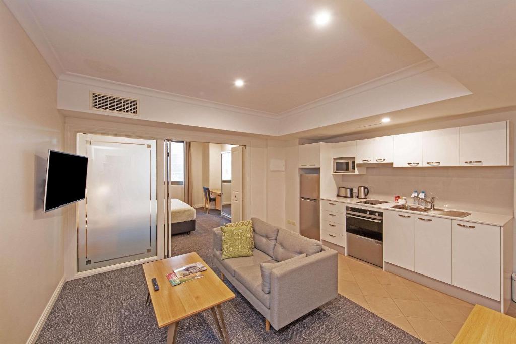 阿德莱德Quality Apartments Adelaide Central的厨房以及带沙发和桌子的客厅。