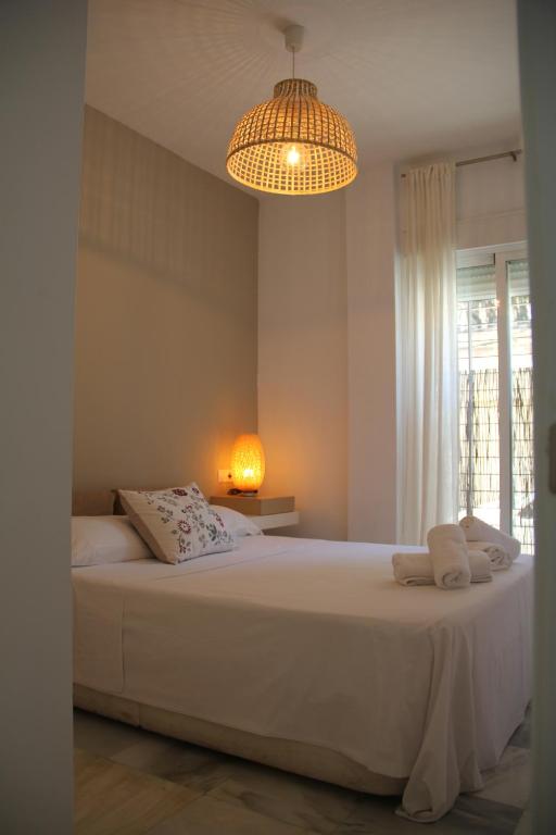 科尔多瓦APARTAMENTO HUERTA LA REINA的卧室配有一张带吊灯的大型白色床。