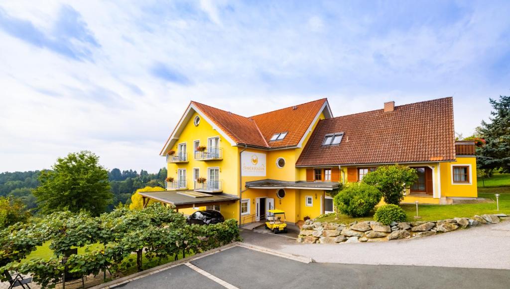 施泰格斯巴赫Golf & Thermenland Sonnenpension Frühstückshotel Burgauberg Stegersbach的棕色屋顶的黄色房子