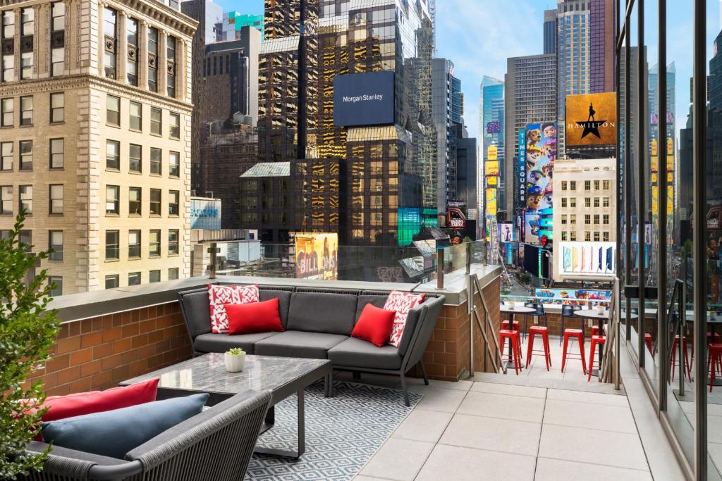 纽约M Social Hotel Times Square New York的阳台设有沙发和桌子,并享有城市美景。