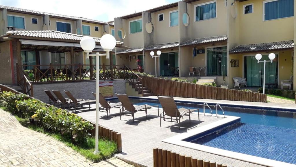 马塔迪圣若昂Casa agradável em condomínio perto da praia.的一个带椅子的庭院和一个游泳池