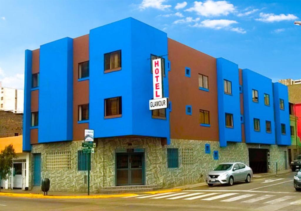 利马HOTEL GLAMOUR的蓝色的建筑,前面有停车位