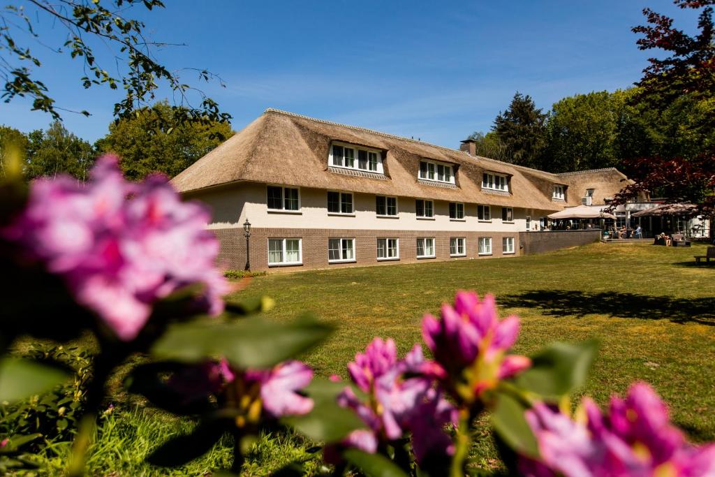 马尔克洛海瑞克堡庄园酒店的一座带粉红色花卉草地庭院的大建筑