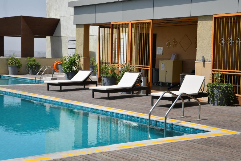 甘地讷格尔Grand Mercure Ahmedabad GIFT City - An Accor Hotels Brand的一座带躺椅的游泳池位于大楼旁