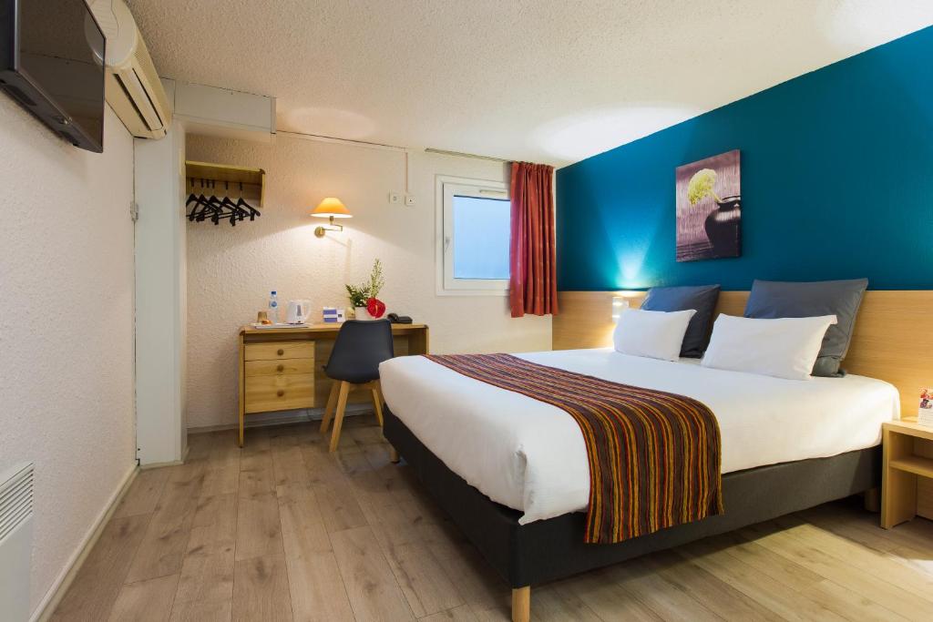 蒙吕松Comfort Hotel Montlucon的酒店客房设有一张大床和一张书桌。