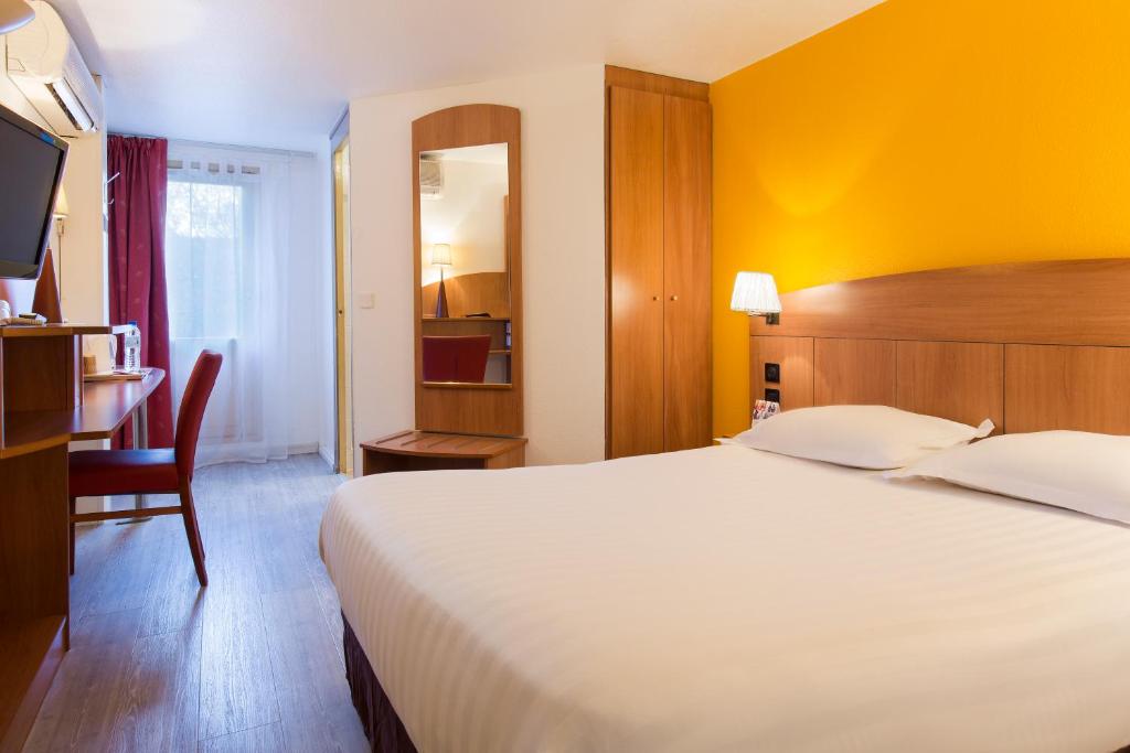 梅朗格勒诺布尔梅兰舒适酒店的酒店客房设有一张大床和一张书桌。