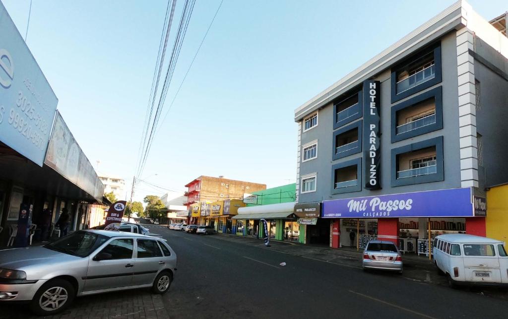 伊瓜苏帕拉迪佐酒店的一条城市街道,汽车停在建筑前