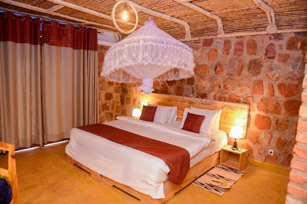 AkageraAkagera Transit Lodge的卧室配有一张石墙内的大床