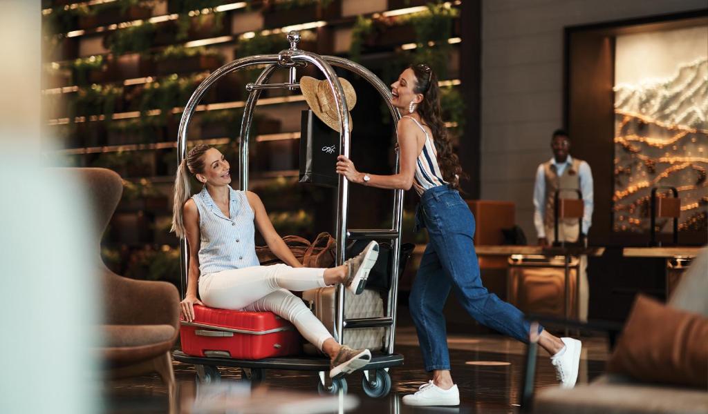 迪拜Revier Hotel - Dubai的两个女人坐在行李车上