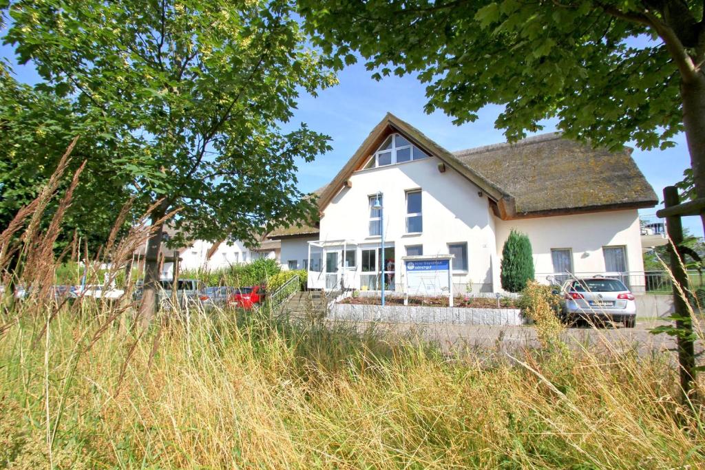 洛布F-1010 Strandhaus Mönchgut Bed&Breakfast DZ 29 strandnah, inkl Frühstück的前面有一辆汽车停放的白色房子