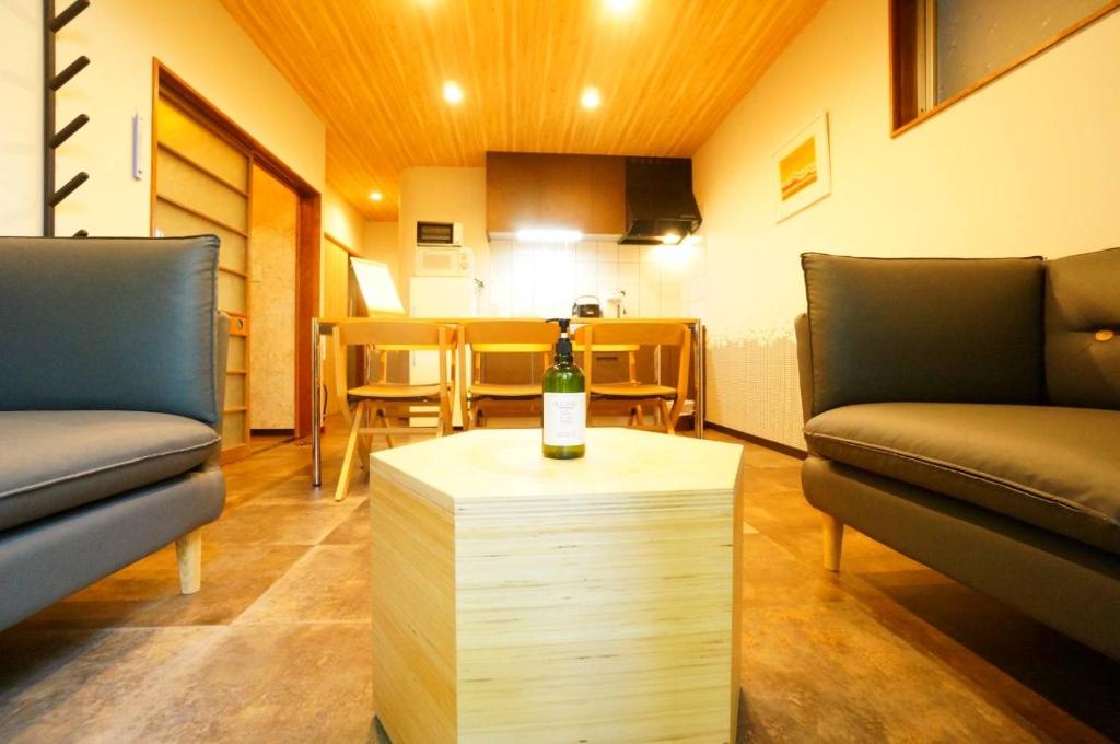高山Momiji Takayama的一间设有两把椅子的房间和一张桌子上的一瓶葡萄酒