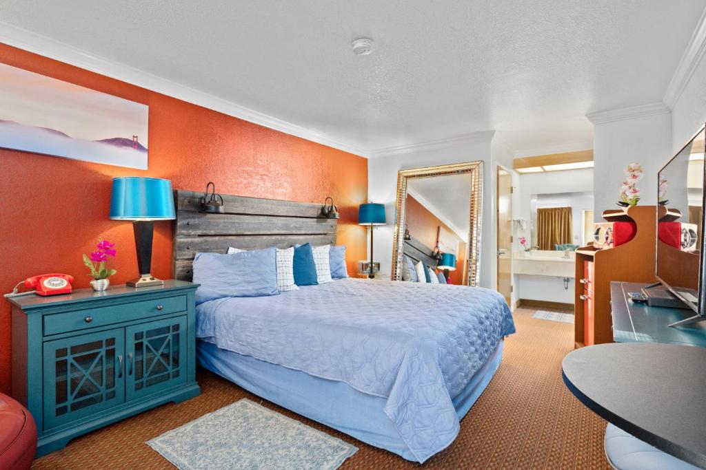 南旧金山阿美莉卡那汽车旅馆的一间卧室设有一张床和橙色的墙壁