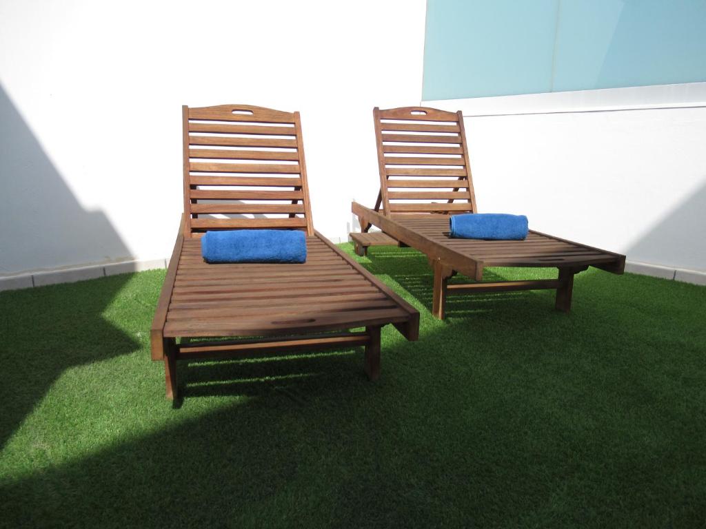 科拉雷侯NÁUTICO Suites, by Comfortable Luxury - Adults Only的两把木椅,蓝色靠垫坐在草地上