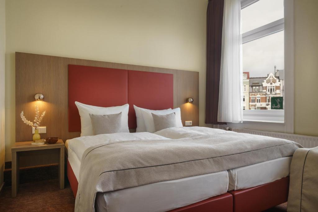 汉堡诺夫北德意志霍夫汉堡酒店的一间卧室配有一张大床和红色床头板