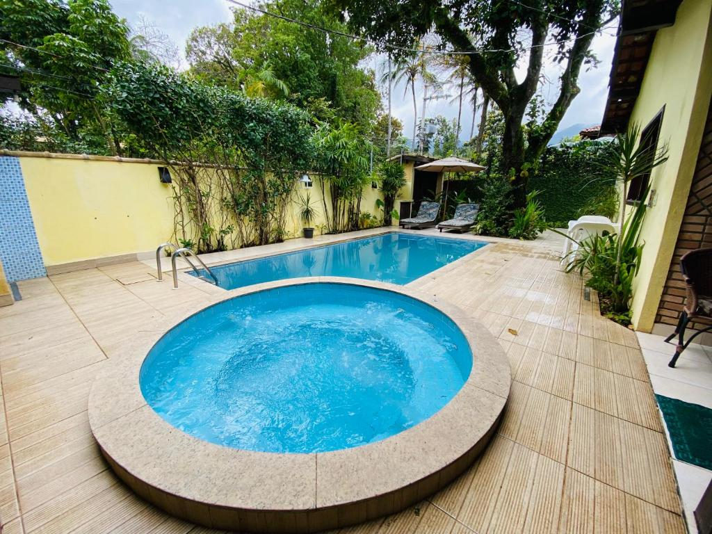 伊利亚贝拉ILHABEACH GUESTHOUSE的庭院里的一个大型蓝色游泳池,铺有木地板