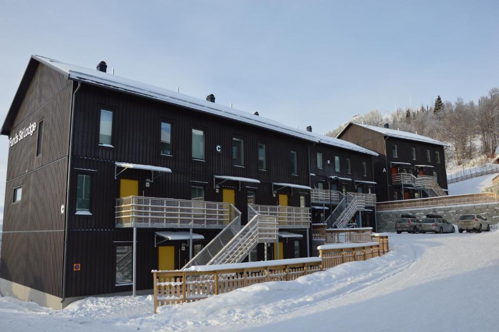 菲奈斯达伦Ski Lodge Funäsdalen的雪中一座黑色的大建筑,有楼梯