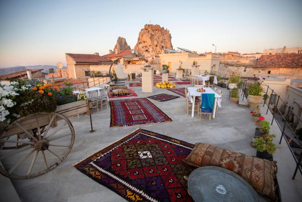 乌奇希萨尔Maze Of Cappadocia Hotel的阳台配有桌椅和地毯。