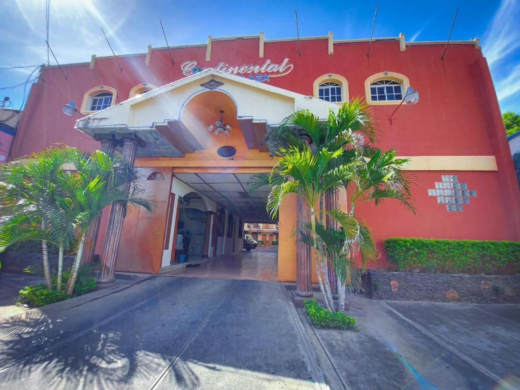 圣米格尔Hotel Continental Plaza的一座红色的建筑,前面有棕榈树