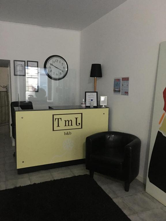 波尔图TMJ住宿加早餐旅馆的一间设有挂在墙上的时钟和椅子的等候室