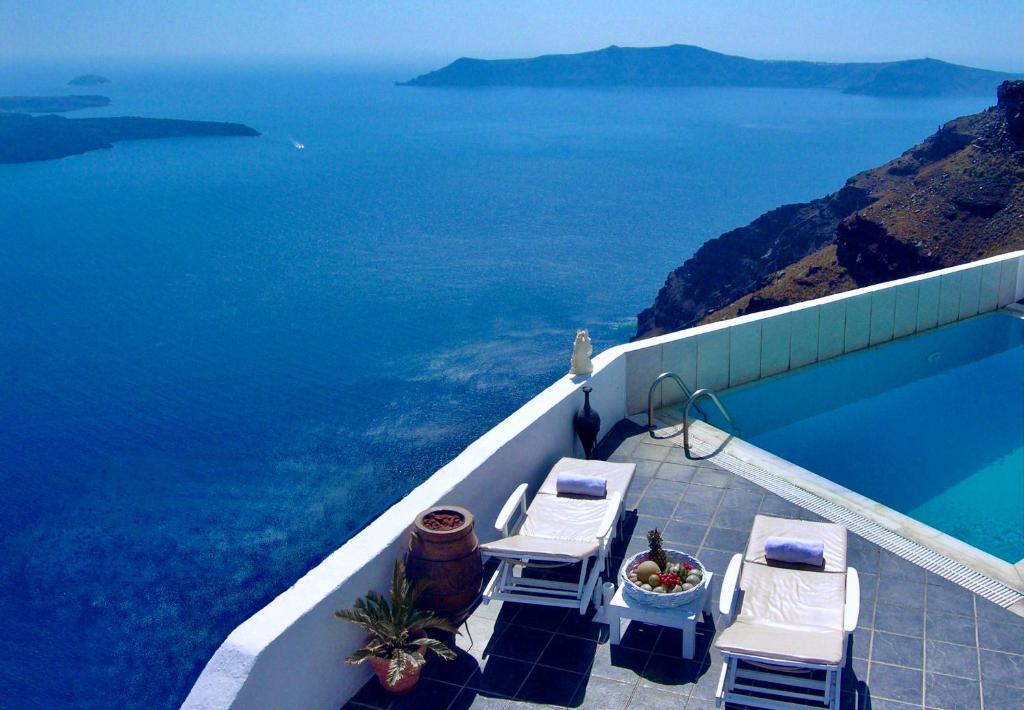 易莫洛林Aeolos Art & Eco Suites Adults Only的一个带两把椅子的游泳池以及大海