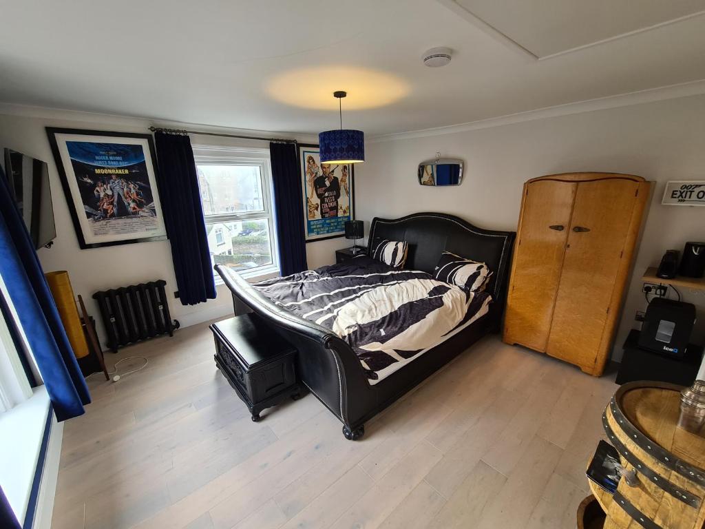 朴次茅斯Southsea Royale Studio, James Bond, Parking, Seafront的一间卧室配有一张床,铺有木地板