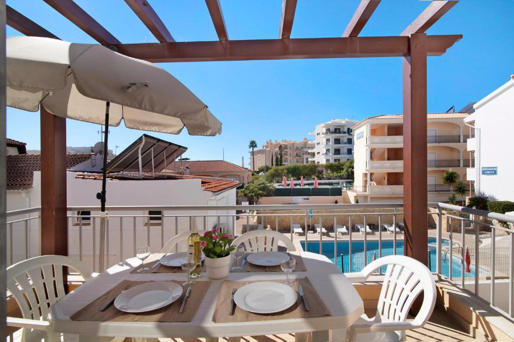 阿尔布费拉Apartamento Água Brisa的阳台上配有带椅子和遮阳伞的白色桌子
