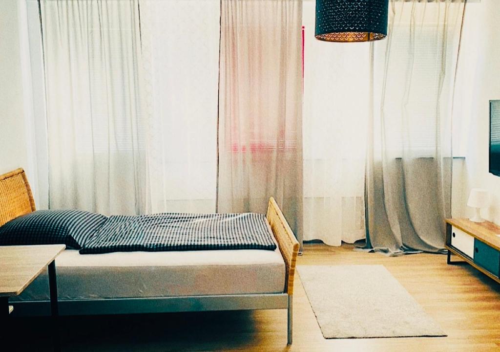 林茨LINZ bellavista Studio-Apartment Landstraße的配有窗帘和桌子的房间的一张床位