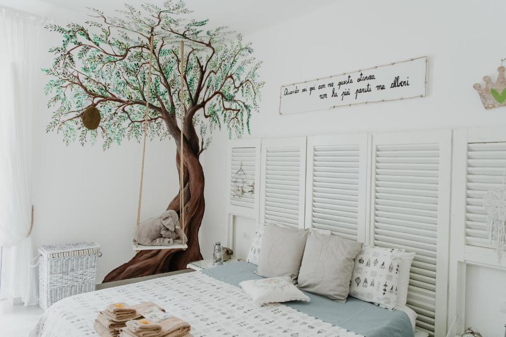 特拉尼Casa Romito的卧室配有一张床铺,墙上挂着一棵树