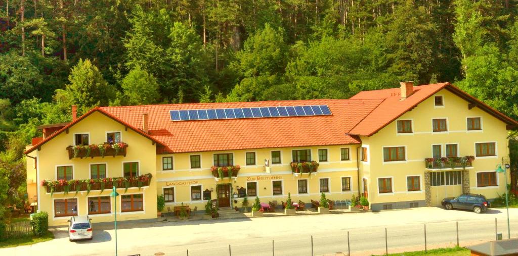Weissenbach an der Triesting加斯托夫苏布鲁腾旅馆的一座大型黄色建筑,拥有橙色屋顶和太阳能电池板