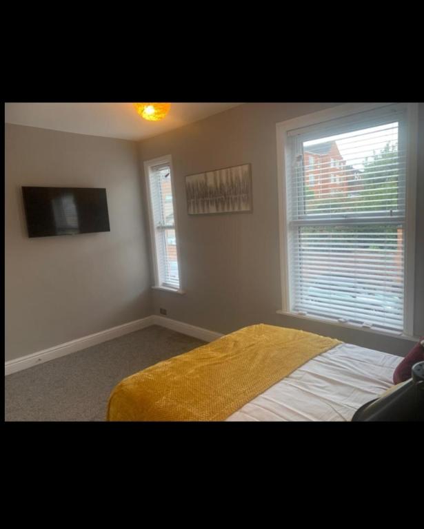 拉格比Beautiful stylish house near town centre的一间卧室设有一张床、一台电视和两个窗户。