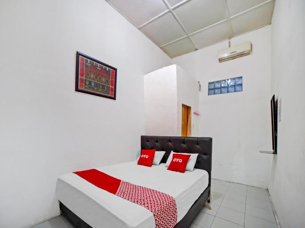 棉兰OYO 90355 Darussalam Inn的白色卧室配有红色枕头的床