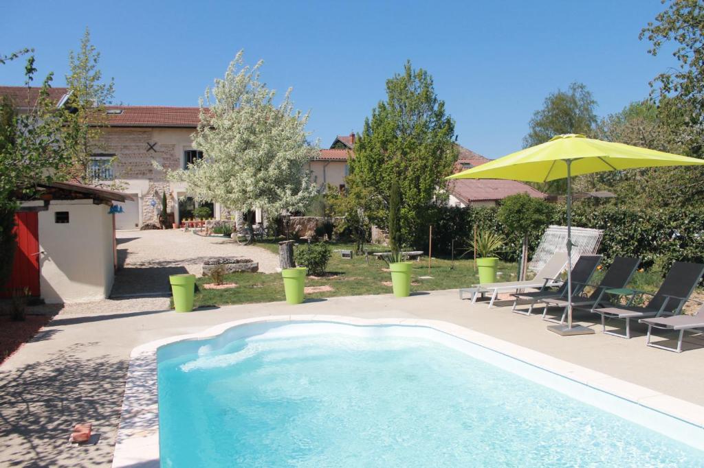DruillatLes Trois Maisons的游泳池配有黄色遮阳伞和椅子