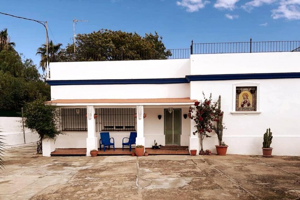 桑卢卡尔-德巴拉梅达Sagrado Corazón - Chalet con piscina, a 25m playa的前面有蓝色椅子的白色房子