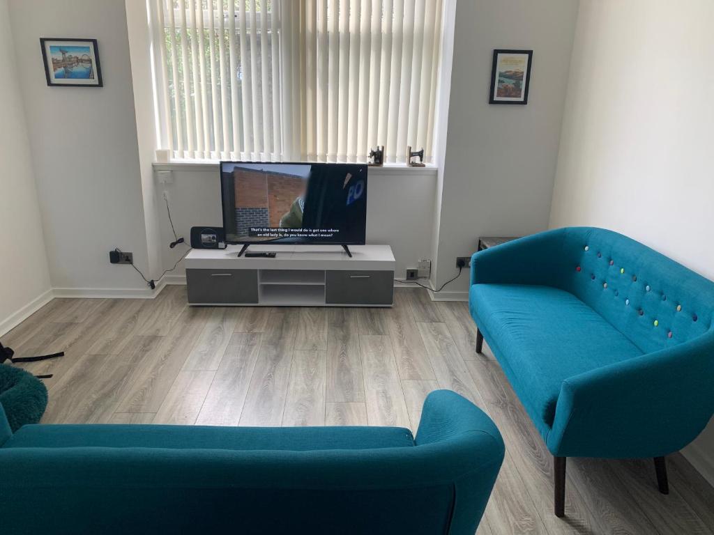 DalmuirThe Cochno Flat, Clydebank的客厅配有2张蓝色沙发和1台电视