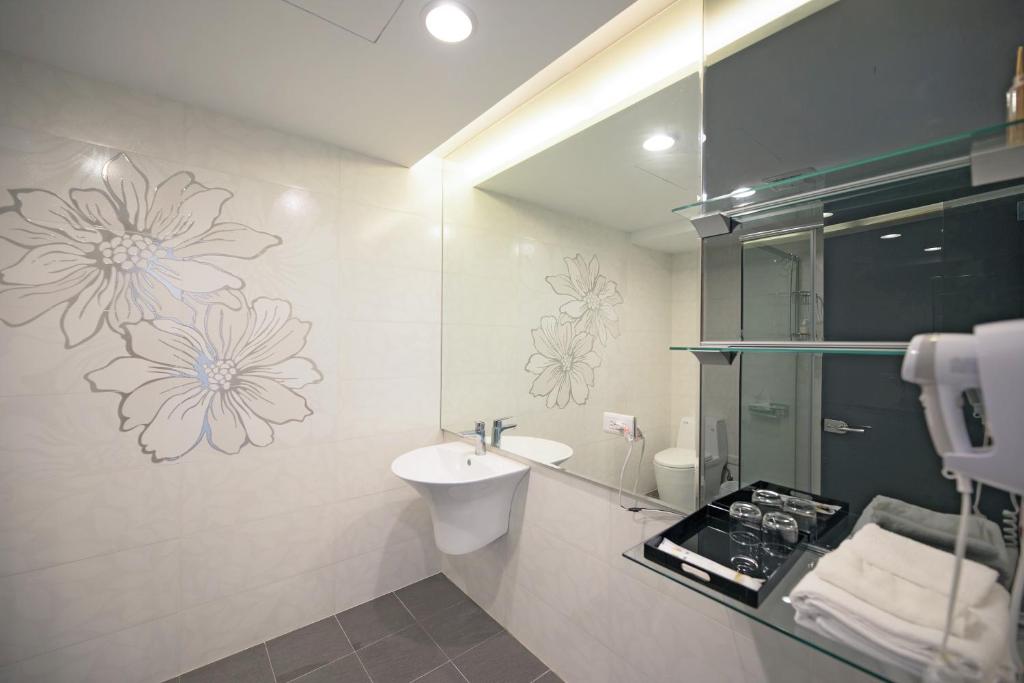 台东松柏文旅Cypress Inn的浴室设有水槽,墙上挂有鲜花的卫生间